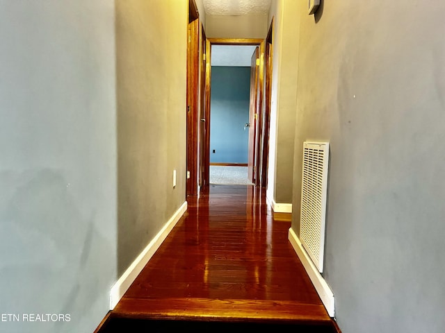 corridor with wood-type flooring and a textured ceiling