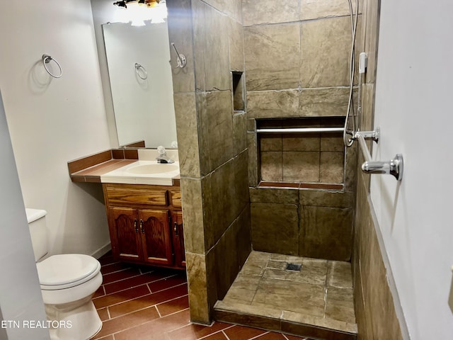 bathroom with toilet, vanity, and tiled shower