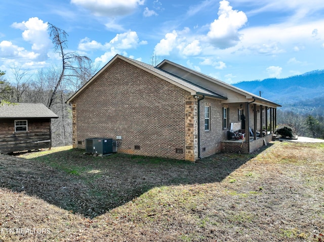 view of side of property featuring a mountain view, a sunroom, and central air condition unit