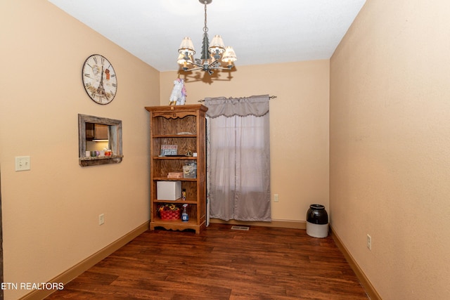 spare room with a chandelier and dark hardwood / wood-style floors