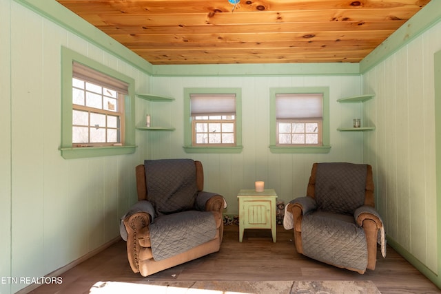 living area featuring wooden walls, light hardwood / wood-style flooring, and wooden ceiling