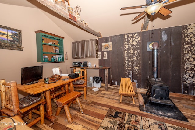 dining area featuring vaulted ceiling, hardwood / wood-style flooring, a wood stove, and ceiling fan