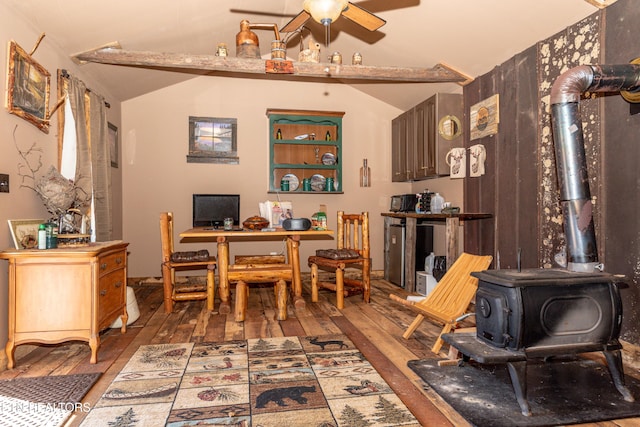 office featuring a wood stove, ceiling fan, wood-type flooring, and lofted ceiling