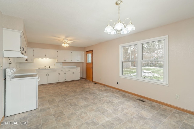 kitchen featuring washer / clothes dryer, white cabinetry, stove, and a healthy amount of sunlight