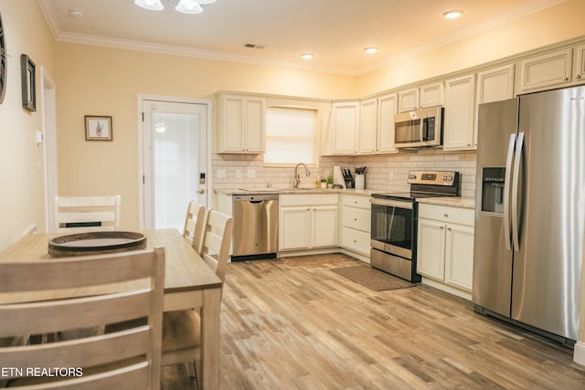 kitchen featuring sink, appliances with stainless steel finishes, tasteful backsplash, cream cabinetry, and light stone counters