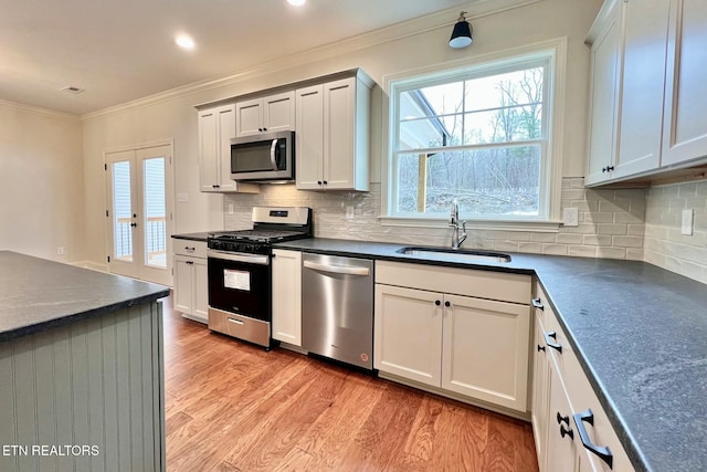 kitchen featuring light wood-type flooring, appliances with stainless steel finishes, white cabinetry, and sink