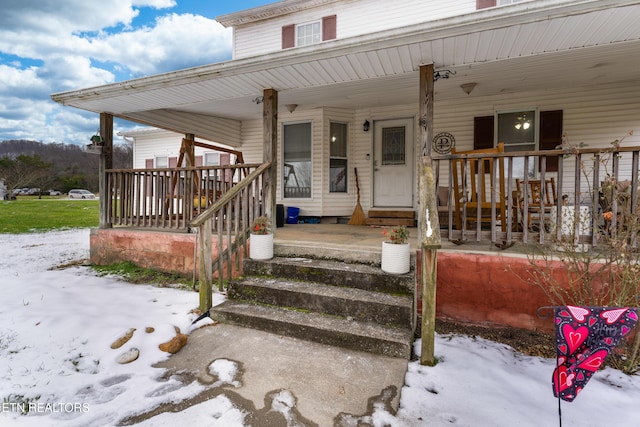 snow covered property entrance with a porch