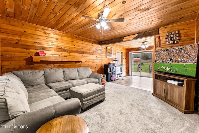 carpeted living room with ceiling fan, wood ceiling, and wood walls