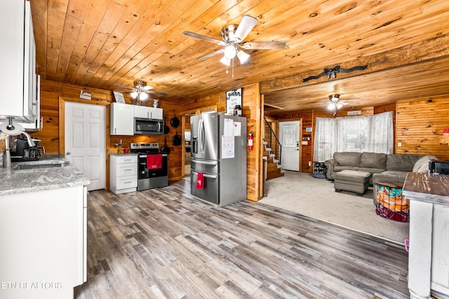 kitchen with wood ceiling, wooden walls, appliances with stainless steel finishes, white cabinets, and sink