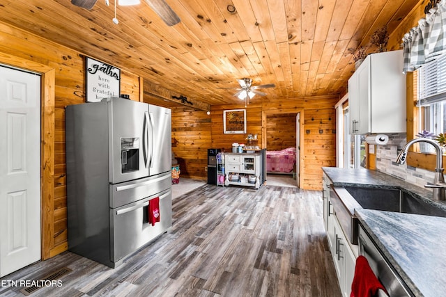 kitchen featuring wood walls, white cabinetry, stainless steel appliances, and wood ceiling