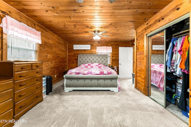 carpeted bedroom with wooden ceiling, a closet, wood walls, and ceiling fan