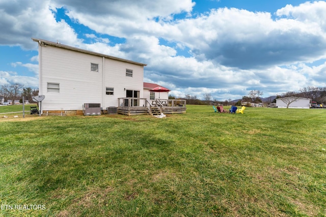 back of property with a lawn, central AC unit, and a deck