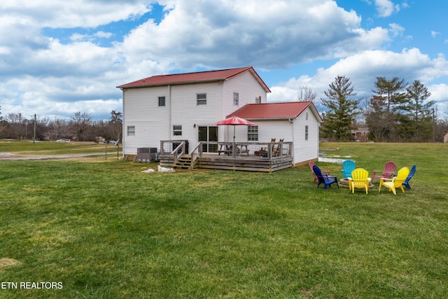 rear view of property with central air condition unit, an outdoor fire pit, a deck, and a yard