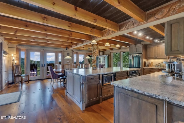 kitchen with french doors, a center island, hanging light fixtures, stainless steel appliances, and light stone counters