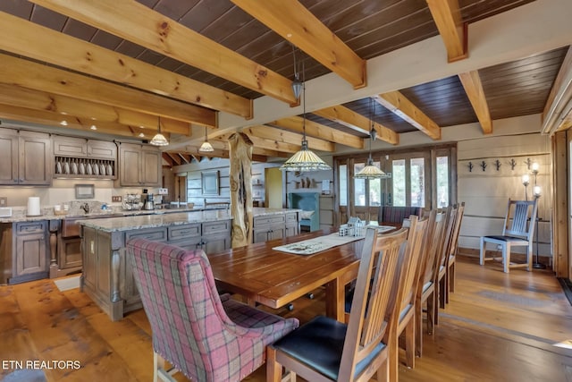 dining area featuring beamed ceiling, light wood-type flooring, and wooden ceiling