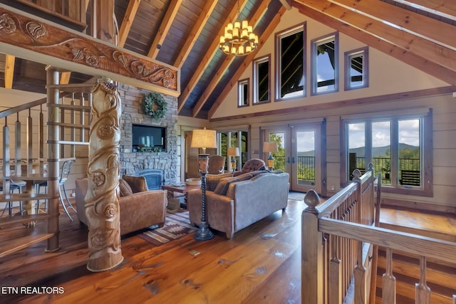 living room featuring beam ceiling, high vaulted ceiling, an inviting chandelier, hardwood / wood-style floors, and a stone fireplace