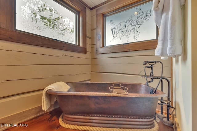 interior space featuring hardwood / wood-style flooring, a bathing tub, and wood walls