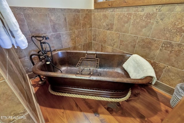 interior details with a tub and hardwood / wood-style floors