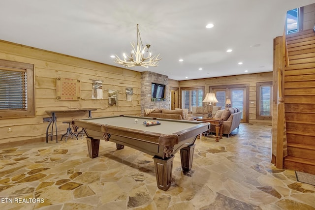 playroom with wood walls, pool table, and an inviting chandelier