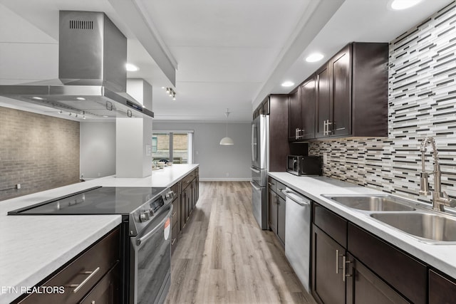 kitchen with stainless steel appliances, decorative backsplash, wall chimney exhaust hood, sink, and decorative light fixtures