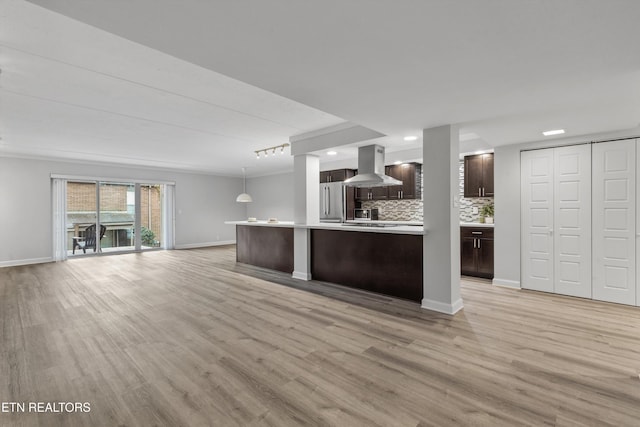 kitchen featuring light wood-type flooring, stainless steel refrigerator, range hood, rail lighting, and pendant lighting