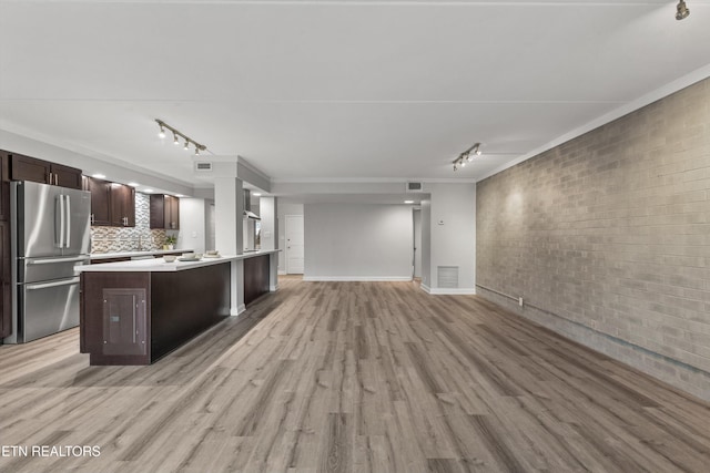 kitchen with light hardwood / wood-style flooring, backsplash, dark brown cabinets, and stainless steel fridge