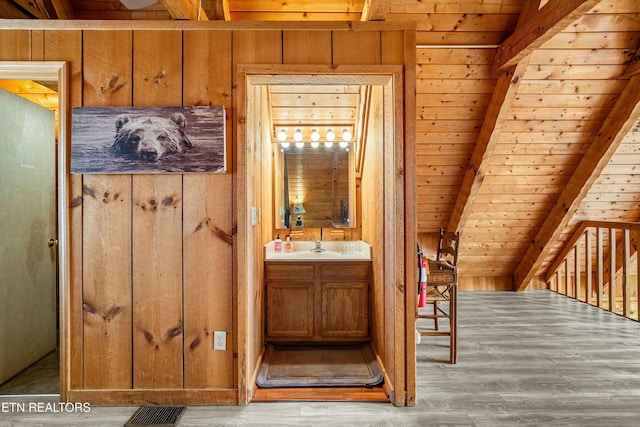 bathroom featuring vanity, wood walls, wooden ceiling, beam ceiling, and wood-type flooring