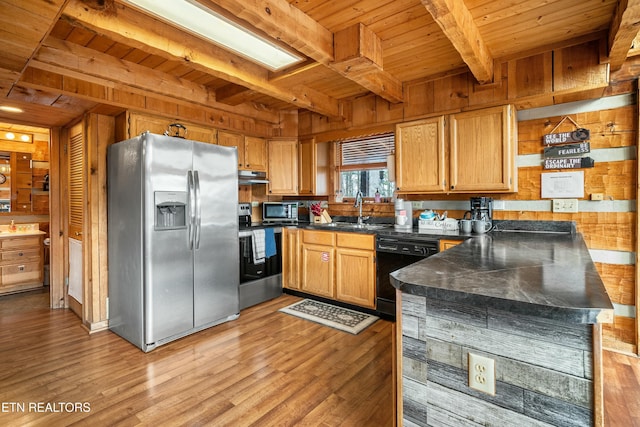 kitchen with appliances with stainless steel finishes, beam ceiling, wood walls, and sink