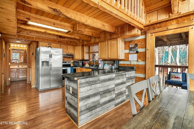 kitchen featuring appliances with stainless steel finishes, light hardwood / wood-style floors, wooden walls, and beam ceiling