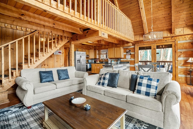 living room with sink, beamed ceiling, wooden walls, wood ceiling, and light wood-type flooring