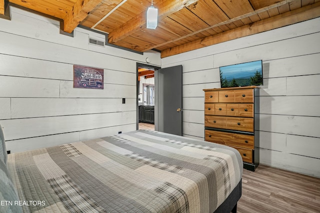 bedroom featuring wooden ceiling, wooden walls, hardwood / wood-style flooring, ceiling fan, and beamed ceiling