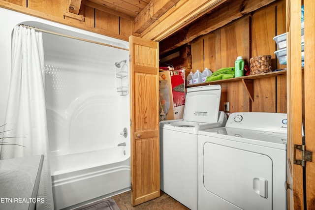 clothes washing area with wood walls, dark tile patterned floors, and separate washer and dryer