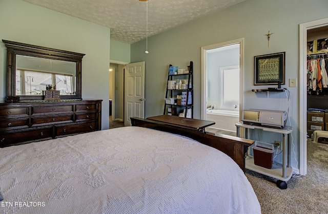 bedroom with attic access, carpet, a walk in closet, a textured ceiling, and a closet