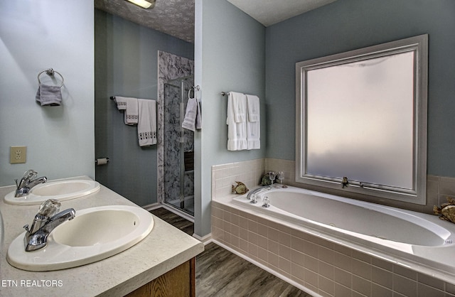 bathroom with wood finished floors, a sink, a bath, and a shower stall