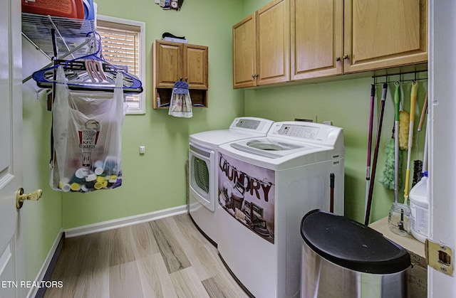 laundry area featuring cabinet space, washing machine and dryer, baseboards, and light wood finished floors