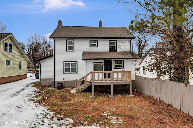 snow covered rear of property featuring a wooden deck and central AC