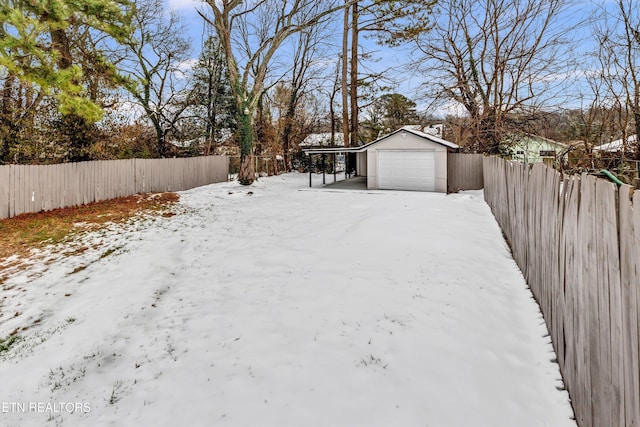 yard layered in snow featuring a carport, a garage, and an outdoor structure