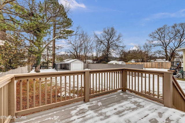 snow covered deck featuring an outdoor structure and a garage