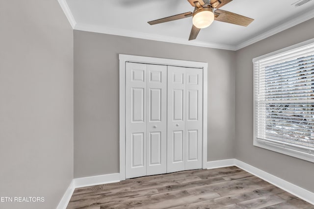 unfurnished bedroom with light wood-type flooring, a closet, ceiling fan, and crown molding