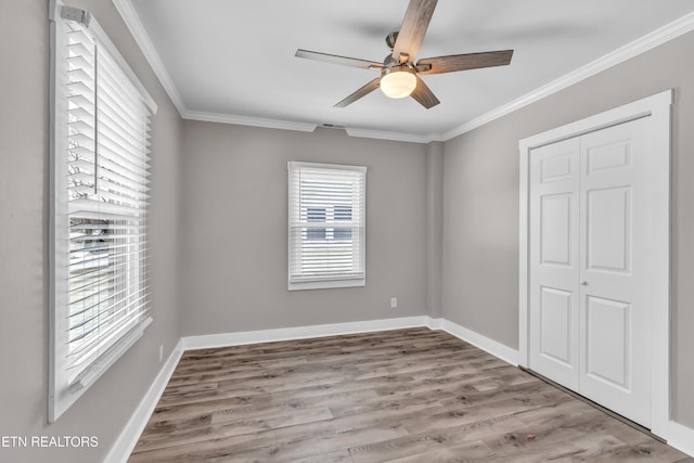 unfurnished bedroom with a closet, ceiling fan, crown molding, and light hardwood / wood-style flooring