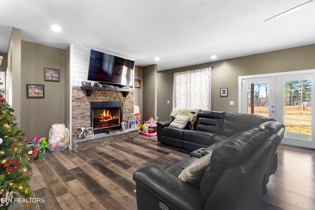 living room with hardwood / wood-style floors, a stone fireplace, and french doors