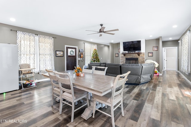 dining space featuring a fireplace, dark hardwood / wood-style flooring, and ceiling fan