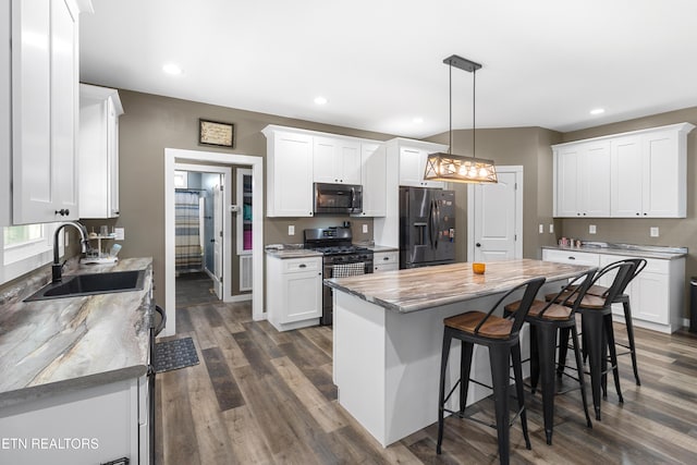 kitchen featuring stainless steel appliances, sink, pendant lighting, a center island, and white cabinetry