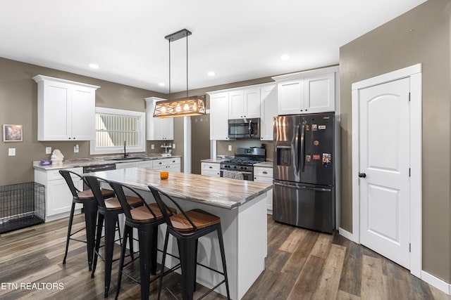 kitchen with stainless steel appliances, white cabinetry, and hanging light fixtures