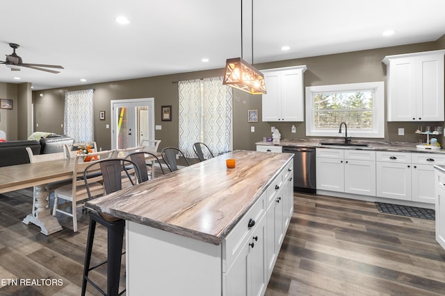 kitchen featuring a center island, white cabinetry, stainless steel dishwasher, and sink