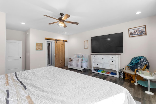 bedroom featuring ceiling fan, a barn door, and dark hardwood / wood-style flooring