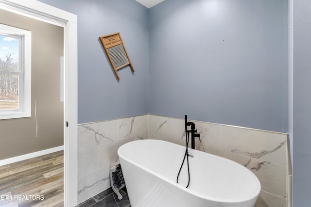 bathroom with a bathing tub and tile walls