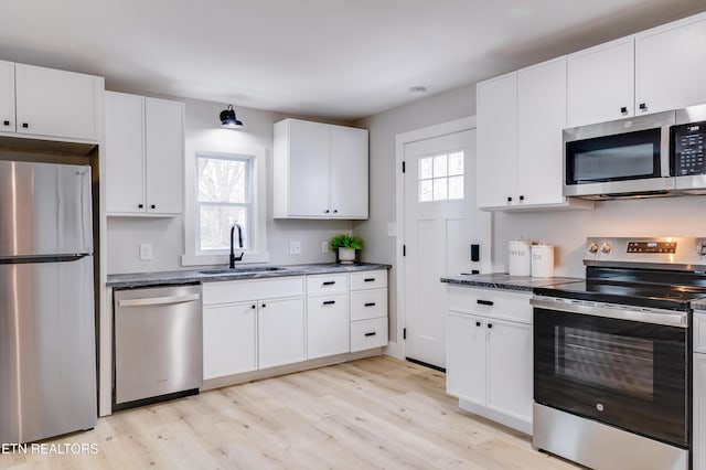 kitchen with light wood-type flooring, appliances with stainless steel finishes, white cabinetry, and sink