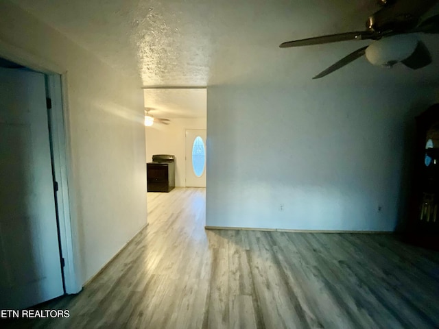 empty room featuring ceiling fan, light hardwood / wood-style flooring, and a textured ceiling