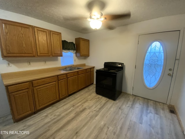 kitchen featuring sink, light hardwood / wood-style flooring, a textured ceiling, and black / electric stove